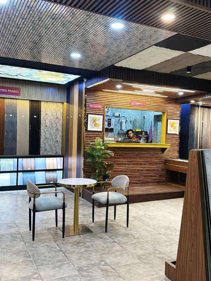 A cozy corner in our showroom, perfect for a detailed discussion about your project. The backdrop features a variety of fluted and marble-finish panels.