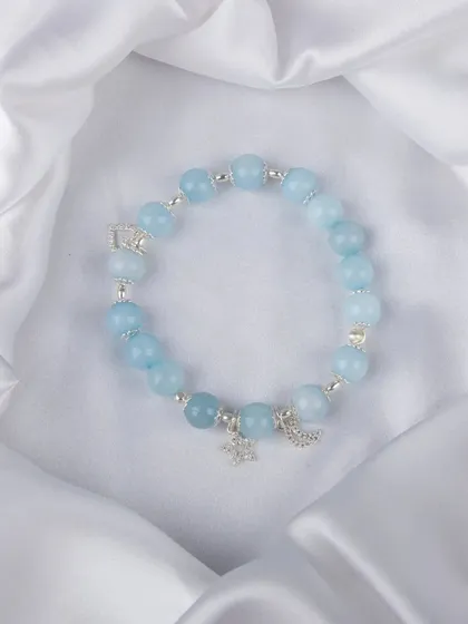 A light blue beaded bracelet with silver moon and star charms.