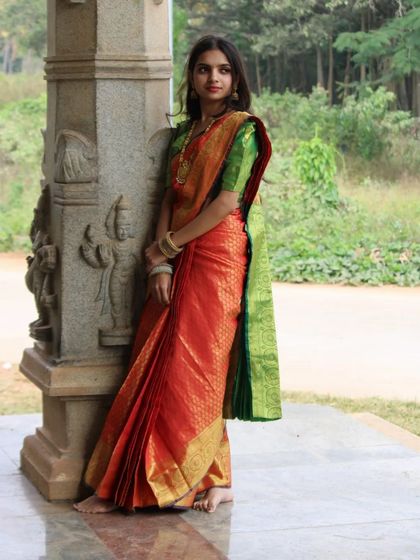 A full-length view of a traditional Kanchipuram saree drape. Notice how the pleats fall evenly and the pallu is secured for a clean silhouette.