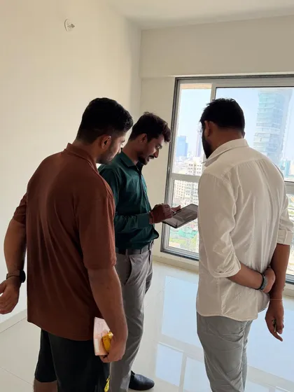 Meeting with new clients on-site. We are looking at the digital plans on a tablet against the backdrop of the Mumbai skyline.