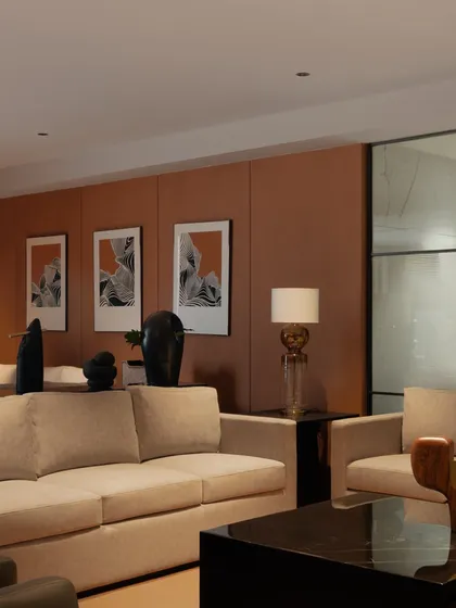 A wide shot of the waiting area, showcasing the harmony between the terracotta-colored walls, the neutral-toned furniture, and the curated artwork. The space feels both professional and comfortable.