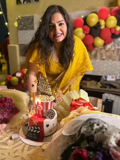 BC Aunty posing happily with her unique 40th birthday cake, which perfectly captured her love for cinema.