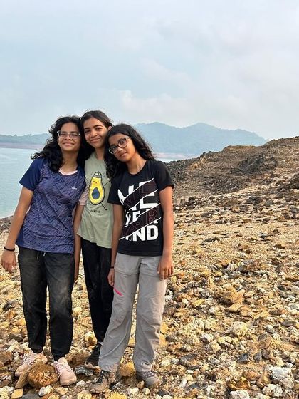 Three friends stand together on the shore, a quiet moment reflecting the friendships made during their adventure.
