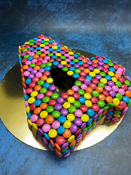 A fun and colorful number cake for a 4th birthday. This "4" shaped cake is completely covered in bright, multi-colored Gems, making it a guaranteed hit with the kids.