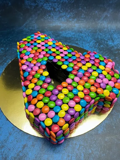 A fun and colorful number cake for a 4th birthday. This "4" shaped cake is completely covered in bright, multi-colored Gems, making it a guaranteed hit with the kids.