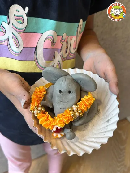 A close-up of a wonderfully detailed clay Ganesha, complete with a delicate garland. It's amazing to see what these tiny hands can create.