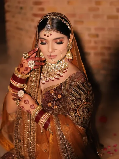 A detailed close-up showing the bride's henna-adorned hands, rings, and the intricate embroidery of her blouse.