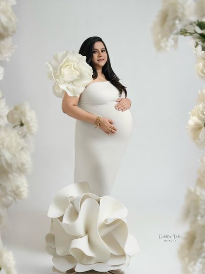 Framed by flowers. This creative composition uses large paper flowers to frame the mother in her sculptural gown, enhancing the theme of blooming and new life.