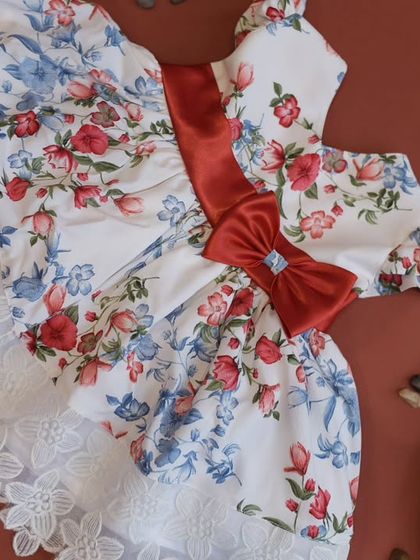 A closer view of the red and blue floral print dress. The lace trim on the hem adds a touch of vintage elegance to this beautiful piece.