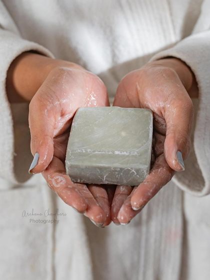 A close-up of a hand model holding a lathery, wet bar of soap. This shot evokes a feeling of clean, natural luxury and is perfect for showcasing the soap's cleansing properties.