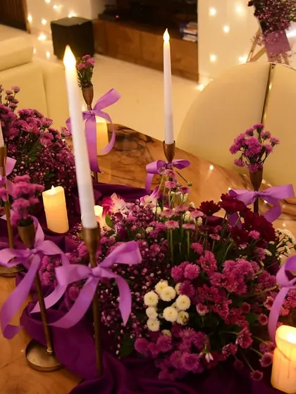 The tablescape for the purple party, featuring a rich purple runner, floral arrangements, and a mix of tall and short candles to create a layered, romantic glow.