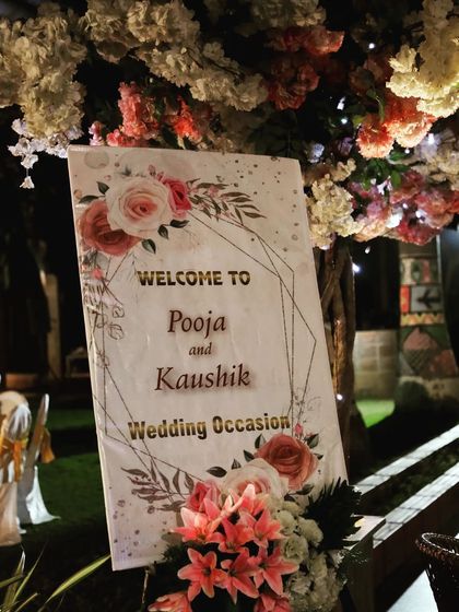 A personalized welcome sign is a wonderful way to greet guests. This sign for a wedding features a modern geometric design with a floral print, complemented by a fresh flower arrangement at its base.