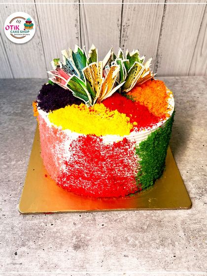 A vibrant Holi cake that looks like it's been dusted with colorful 'gulaal'. The top is adorned with edible, colorful splashes, making it a true festival of colors.