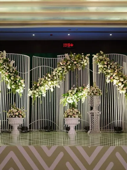 Modern elegance is about clean lines and impactful design. This reception stage features a unique, wave-like white backdrop adorned with delicate floral arrangements, creating a look that is both minimalist and incredibly chic.