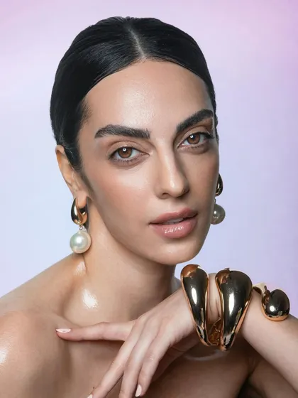 This close-up beauty shot highlights a glossy skin finish and perfectly groomed, bold brows. This look is ideal for jewellery or cosmetic ads where a polished, high-shine effect is desired.