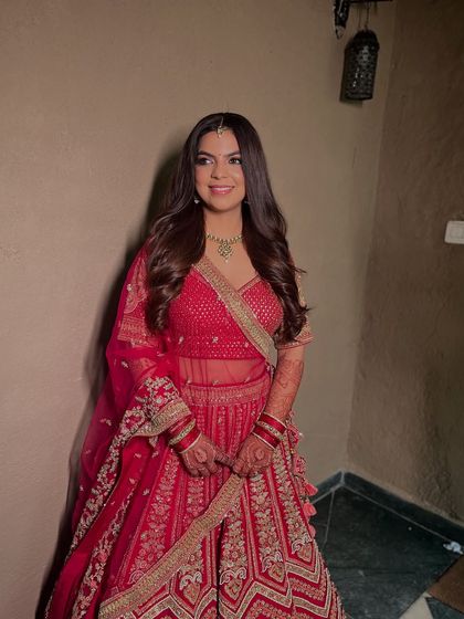 A full-length shot of Ekta in her beautiful red lehenga. The soft, romantic makeup perfectly complements the modern silhouette of her outfit.