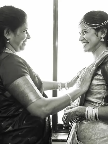 A happy black and white photo of a mother and daughter sharing a smile as they get ready.