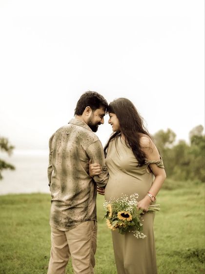 A beautiful, intimate moment with the couple touching foreheads, framed by the serene lakeside. Her holding the sunflowers adds a touch of natural beauty.