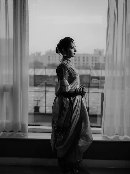 A stunning black and white silhouette of the bride standing by a window, creating a dramatic and contemplative bridal portrait.