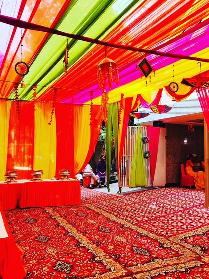 A wide view of the tent interior, showing the catering setup and guest seating under a colourful draped ceiling.