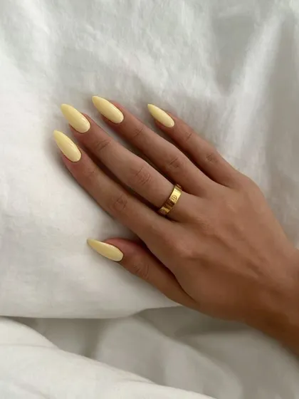 A simple and chic manicure in a soft, pastel yellow. The long almond shape is elegant, and the color is perfect for a subtle, minimalist look.