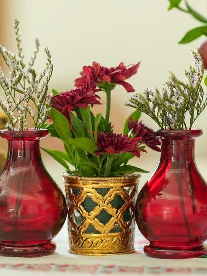 A close-up of the small red and gold vases used in the tablescape, each holding a simple yet elegant floral arrangement.