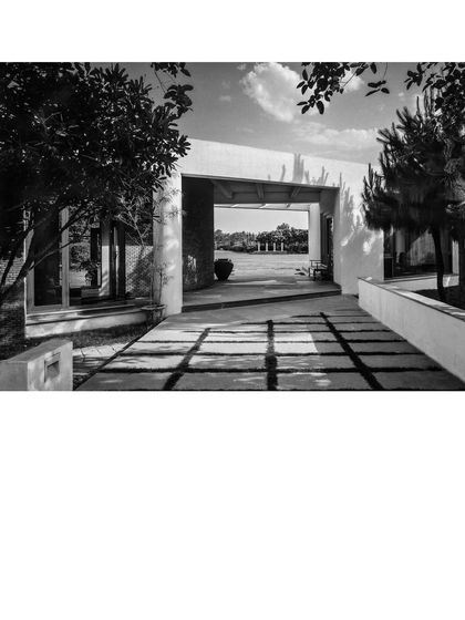 A framed view through an opening in the House of Axes, looking out onto a landscaped court. The architecture is designed to create deliberate perspectives, guiding the eye and creating a sequence of experiences as one moves through the property.