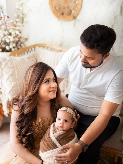 A beautiful interactive shot of new parents with their awake and curious newborn, captured in my cozy boho studio setting.