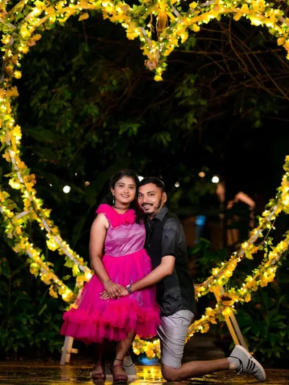 A romantic photo framed by a giant heart-shaped arch made of yellow flowers and lights. This is a perfect prop for a love-themed pre-wedding shoot.