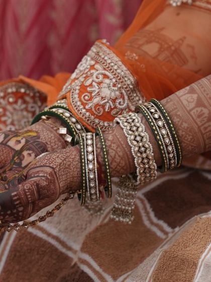 A candid shot from a wedding ceremony, showing the beautiful contrast between the dark mehendi stain and the bride's colorful bangles.