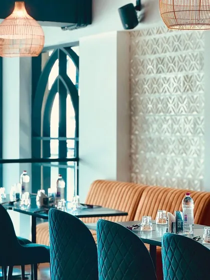 Our dining space is arranged to offer both communal energy and private corners. The combination of plush teal chairs and warm, upholstered booth seating caters to different group sizes and preferences.