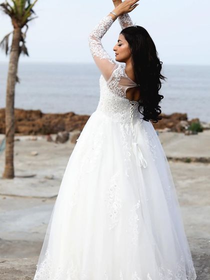 A full-body shot of the white lace gown, showing its elegant silhouette against a beach backdrop.
