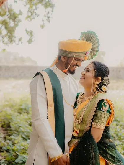 A classic romantic portrait of the couple gazing into each other's eyes. The natural lighting and green backdrop enhance the warmth and intimacy of the moment.