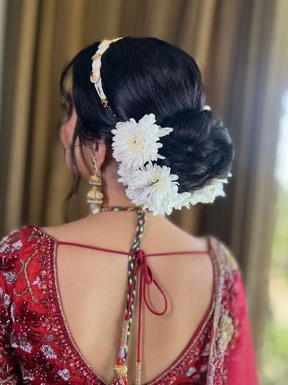The back view of this phera-ready hairstyle shows a clean, elegant bun decorated with large white chrysanthemums for a simple yet impactful statement.