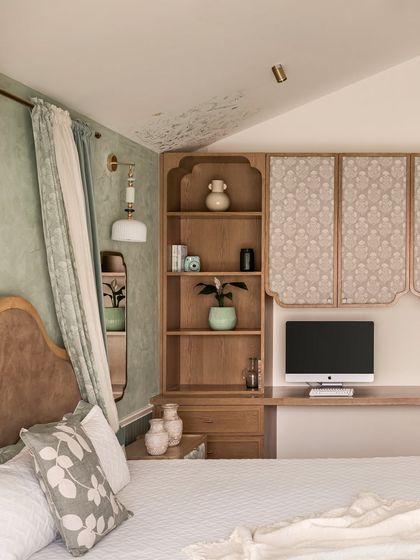 A detail of the custom cabinetry, which features scalloped edges and fabric-paneled doors. A hand-painted botanical mural on the ceiling adds a whimsical, artistic touch.