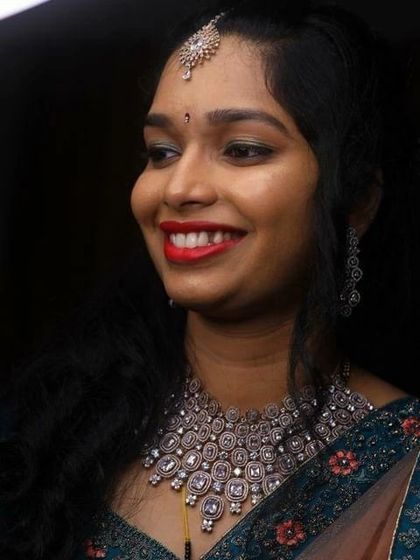 A happy bride at her reception. Her look features a bright red lip, softly curled hair, and sparkling diamond-style jewellery, creating a fresh and modern bridal style.