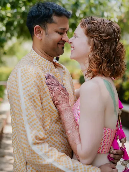 A happy, sun-drenched photo from their welcome event. The bride's custom Banarasi lehenga skirt with pops of pink is paired with comfy sneakers for a fun, modern Indian look.