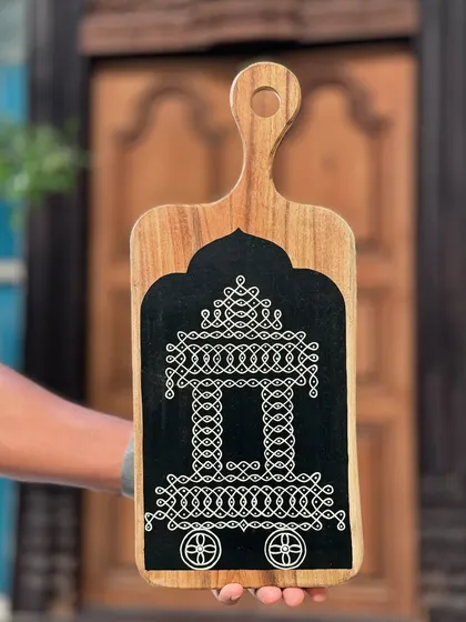 This hand-painted wooden platter features a traditional Rangoli design of a temple chariot. It’s a versatile piece that can be used as a centerpiece or hung as wall art, blending sacred geometry with functional style.