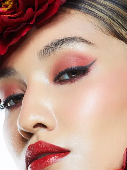 A close-up of a classic red look with a sharp winged liner and a perfectly blended red eyeshadow.