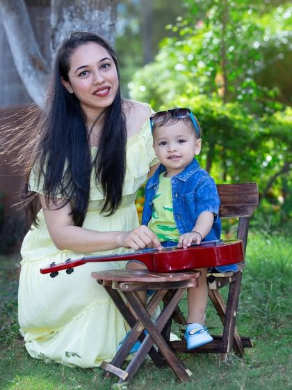"Let's play music with Mom." A mother and her son sit together with a small red guitar, ready to make some music and memories in the park.