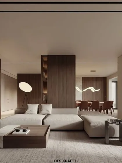 This open-plan living space embodies the principles of warm minimalism. We combined a low-profile modular sofa with rich walnut wood paneling and integrated shelving to create a home that feels expansive, organized, and deeply calming.