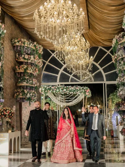 The bride's entry under a beautiful phoolon ki chadar, walking towards the grand, flower-adorned mandap.
