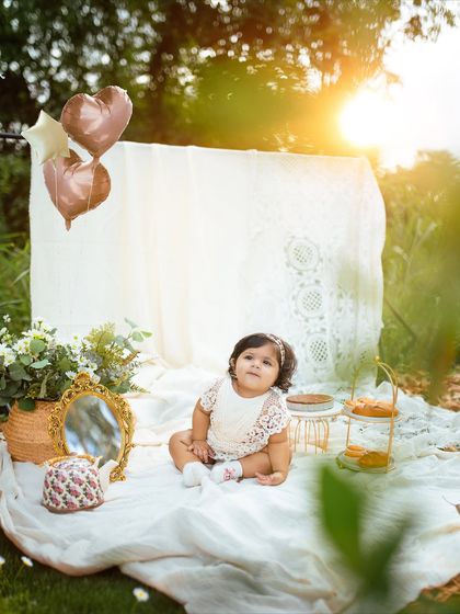 A beautiful portrait of the birthday girl sitting amongst her picnic props, looking so peaceful and sweet as she turns one.