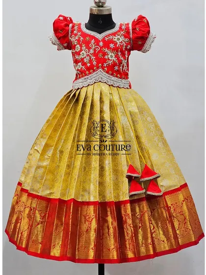 A grand red and gold lehenga. The blouse is heavily embroidered, and the skirt is a gold brocade with a traditional red Kanchi border.