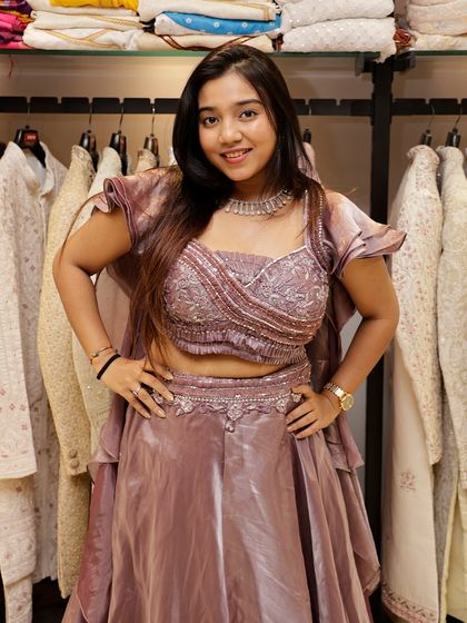 This Indo-Western lehenga is all about modern fusion. The dusty pink outfit features a stylishly draped blouse with ruffled sleeves and a layered skirt, making it a trendy choice for a cocktail party or reception.