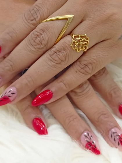 A full view of the sophisticated red nails with sheer, leafy accent art.