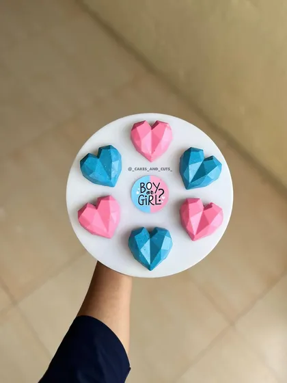 Geometric heart-shaped cakesicles in pink and blue for a "Boy or Girl?" themed celebration.
