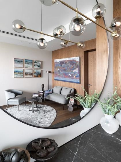 A creative shot reflecting the guest room's seating area in the large circular mirror. This view highlights the layered design, from the art on the walls to the sculptural lighting and comfortable, stylish furniture.