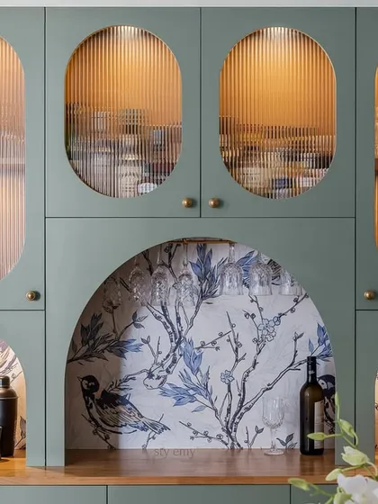 A detailed view of the sage green crockery unit, highlighting the artistic use of curves and patterns. The combination of fluted glass, arched niches, and delicate wallpaper transforms this storage piece into a design statement.