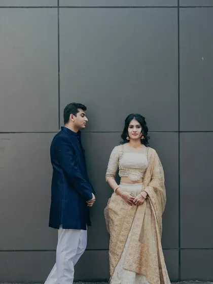 This photo captures the couple's style. Her makeup is soft and timeless, complementing her classic white and gold lehenga for their engagement photos.